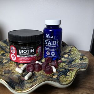 VitaUp NAD+ and biotin gummies displayed on decorative tray showing supplement routine for women over 40 that works across two climates