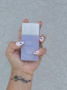 Hand holding a lavender Naked Sundays sunscreen box