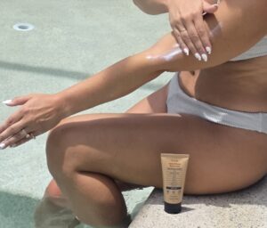 Applying sunscreen to a shoulder with the tube nearby