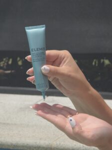 Squeezing sunscreen from a light blue tube onto a fingertip