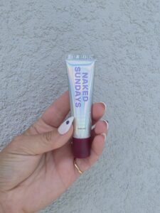 Hand holding a Naked Sundays sunscreen tube