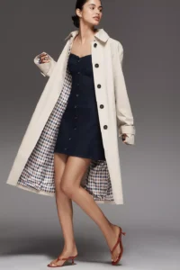 Model wearing a khaki trench coat over a navy dress