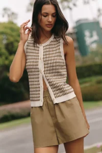 Woman in a cream tweed knit vest and olive green shorts