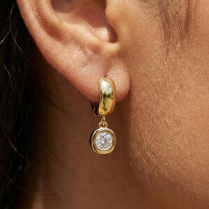 Close-up of a woman over 40 wearing a gold huggie hoop with a small crystal charm