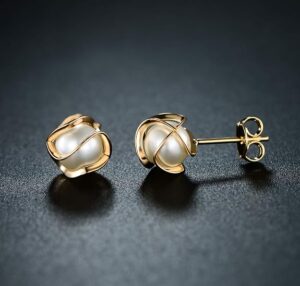 Gold caged pearl stud earrings on a dark background