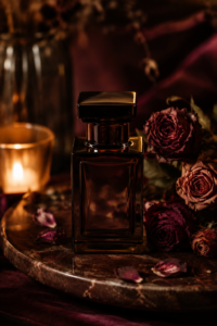 Dark perfume bottle among deep red roses in candlelight — a romantic scent stacking combination