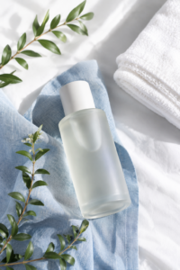 Frosted fragrance bottle on soft fabric with fresh eucalyptus sprigs — a fresh, polished scent stack