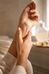 Woman over 40 applying layered fragrance to her wrist pulse point